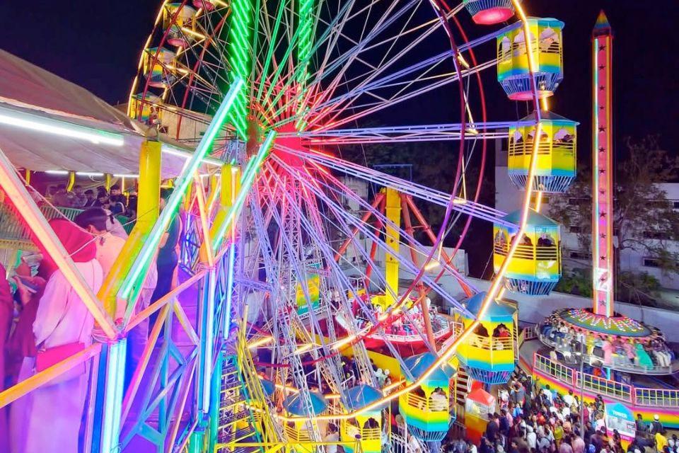 A vibrant ferris wheel at night, filled with people and illuminated by colorful lights at Amusement Rides Hyderabad.